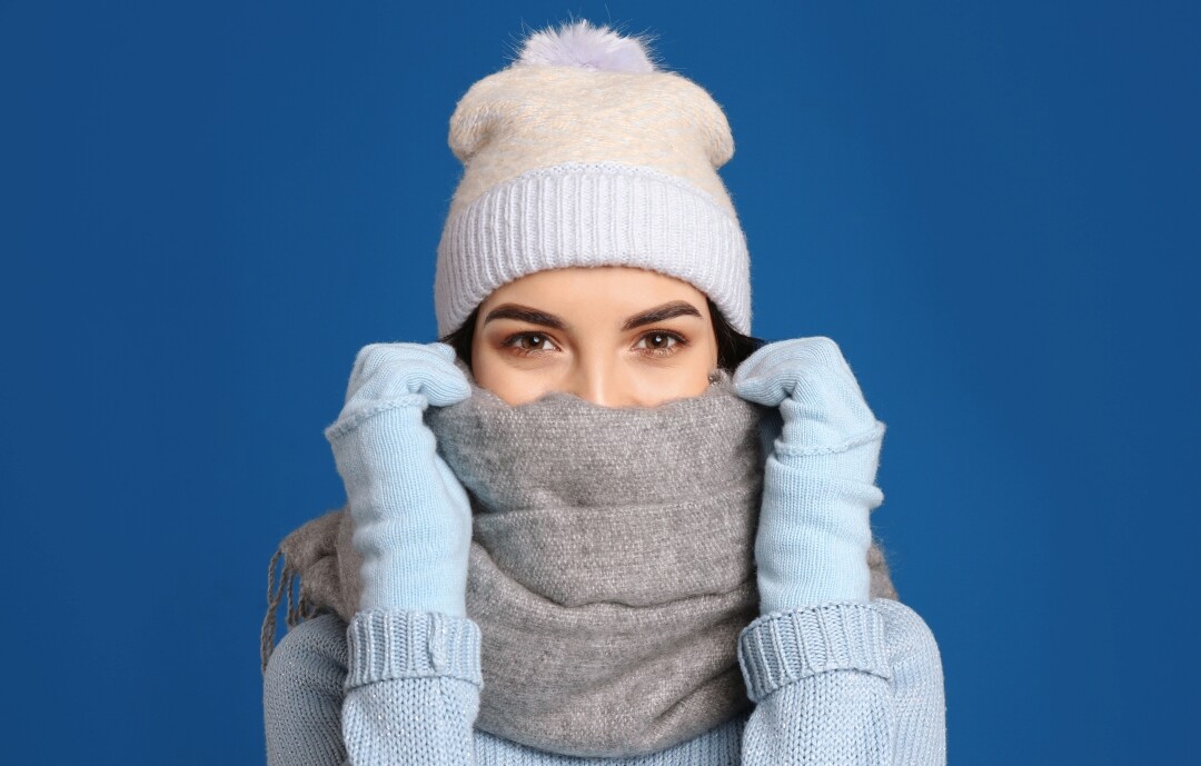 Frau mit weißer Mütze und grauem Schal auf blauem Hintergrund