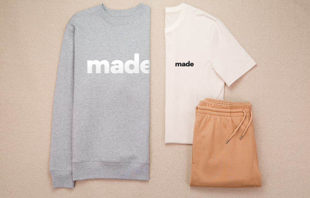 Pullover und T-Shirt mit Flexdruck sowie eine Hose auf beigem Hintergrund