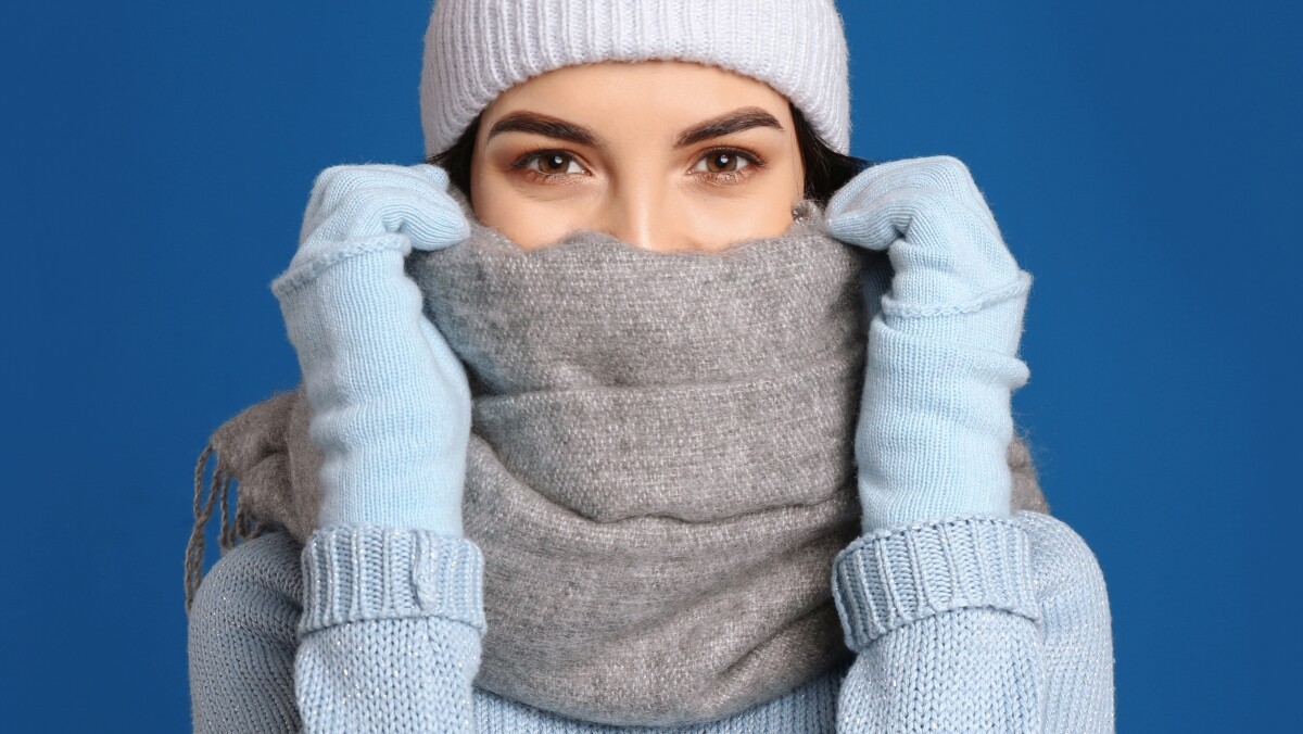 Frau mit weißer Mütze und grauem Schal auf blauem Hintergrund
